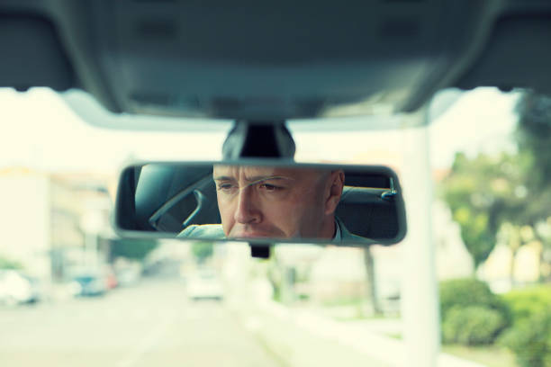 istock Closeup portrait serious young man driver reflection in rear view mirror isolated interior car windshield background 682547558