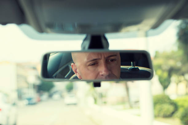 istock Cropped horizontal photo image, rear mirror view reflection of handsome elegant serious business man drives a car looking to the road 682547874