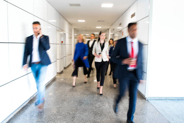 Business people in a blurred motion Group of business people walking in a corridor of business building in a blurred motion. defocused office business motion stock pictures, royalty-free photos & images