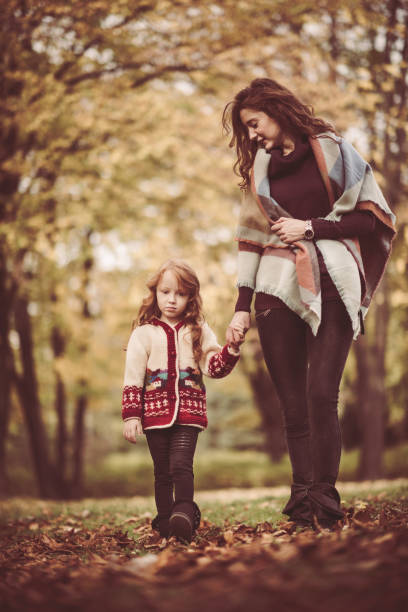 istock Mother and daughter taking a walk through autumn park. 682559240