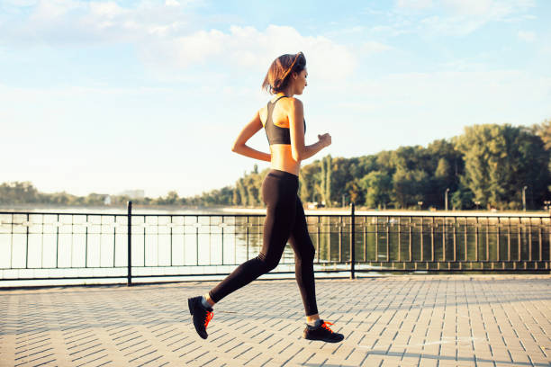 istock Woman running by the lake at sunset 682559448