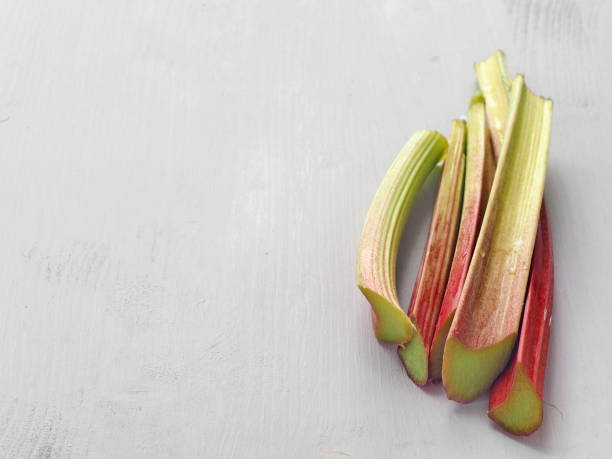 Culinary background. Stems of fresh rhubarb upon wooden table. stock photo