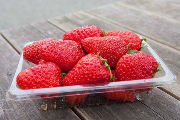 istock fresh strawberry in plastic box . with wooden table . 682560356