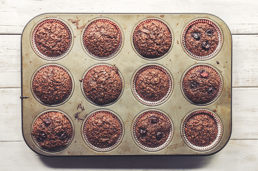 Chocolate bran muffins with cherries, in old, grunge looking, tin tray, top view