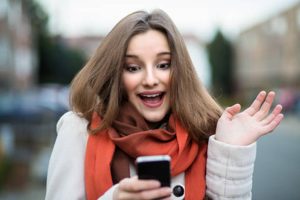 istock Euphoric woman watching her smart phone outdoors city background 682563768