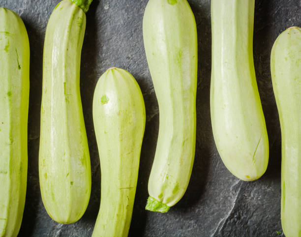istock Green young zucchini on a dark stone background. Geometric layout. 682564014