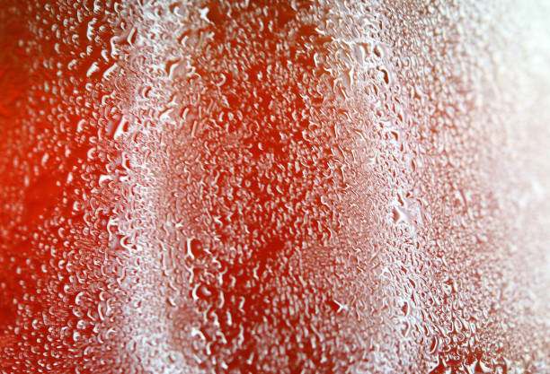 istock Macro shot of water drops texture on a vibrant red bottle with selective focus 682572036