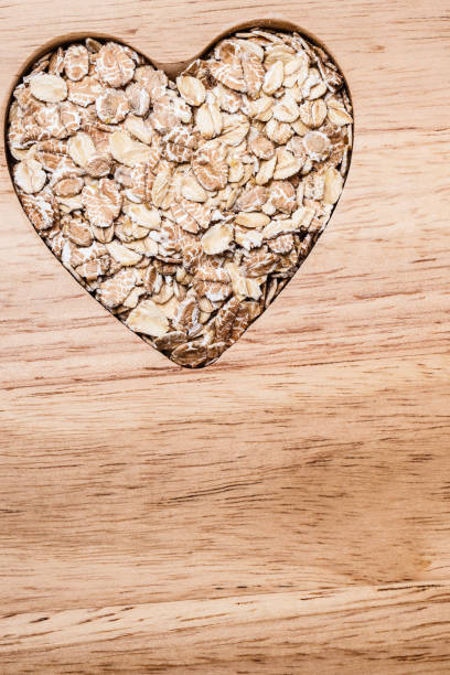 coração do cereal da aveia dado forma na superfície de madeira. - oatmeal breakfast healthy eating cholesterol - fotografias e filmes do acervo