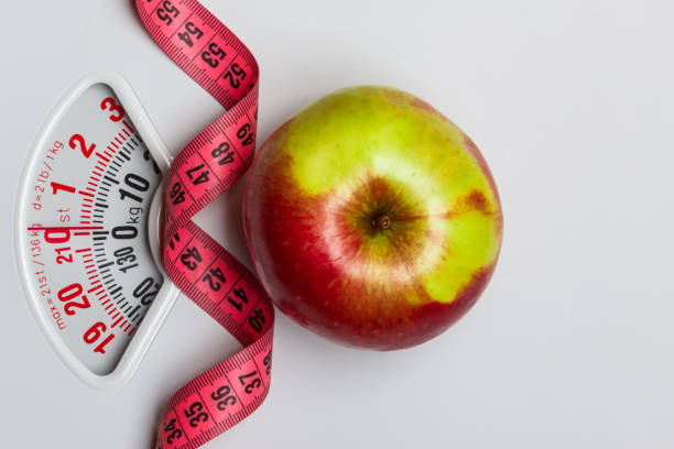 istock Apple with measuring tape on weight scale. Dieting 682578804