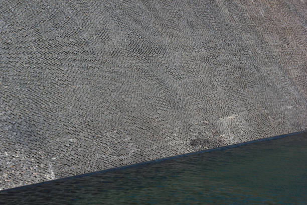 Wall fountain with water flowing down the textured stone surface, glistening in the sun and creating relaxing noise.