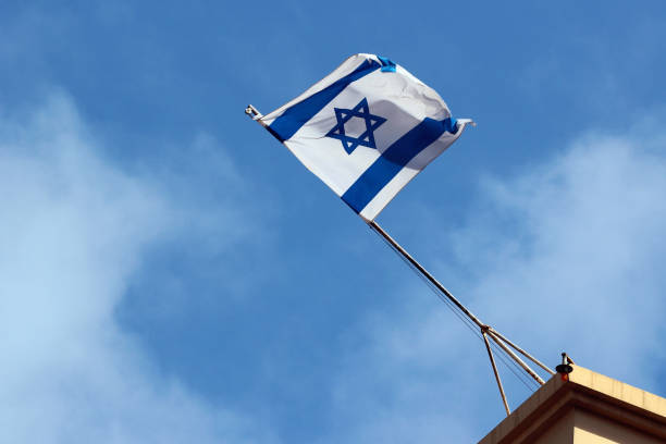 istock Israeli flag on a rooftop against blue sky background 682584016