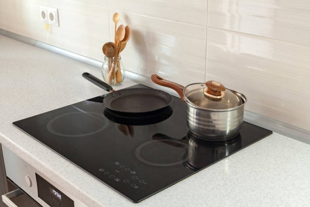 open saucepan, pan and wooden spoons in modern kitchen with induction stove - stove ceramic burner electricity imagens e fotografias de stock