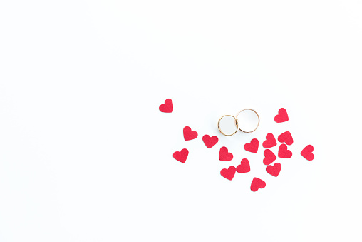 Top view of golden wedding rings and pink hearts symbols isolated on white, wedding rings background