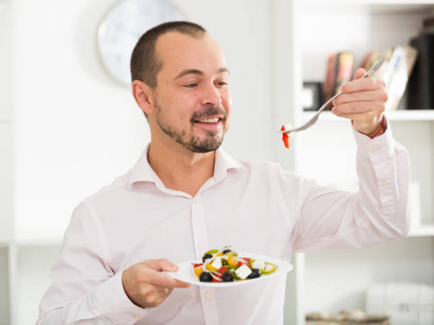 istock Smiling man looking at greek salad 682628698