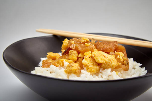 Close up view of Stir fried salted turnip with egg served with cooked rice in a dark bowl , Simple Thai food, selective focus.