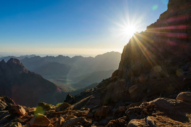 ägypten, sinai, berg moses. blick von der straße, auf der pilger den berg moses erklimmen und morgendliche morgensonne mit strahlen am himmel. - moses stock-fotos und bilder