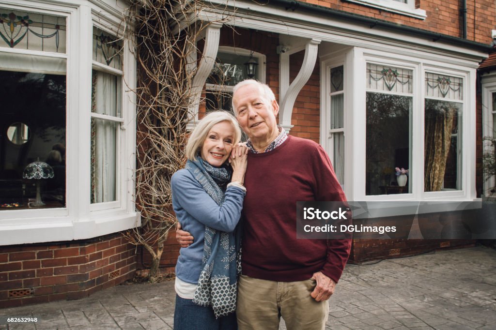 Happy Senior Couple Senior couple are smiling for the camera while standing in front of their home. House Stock Photo