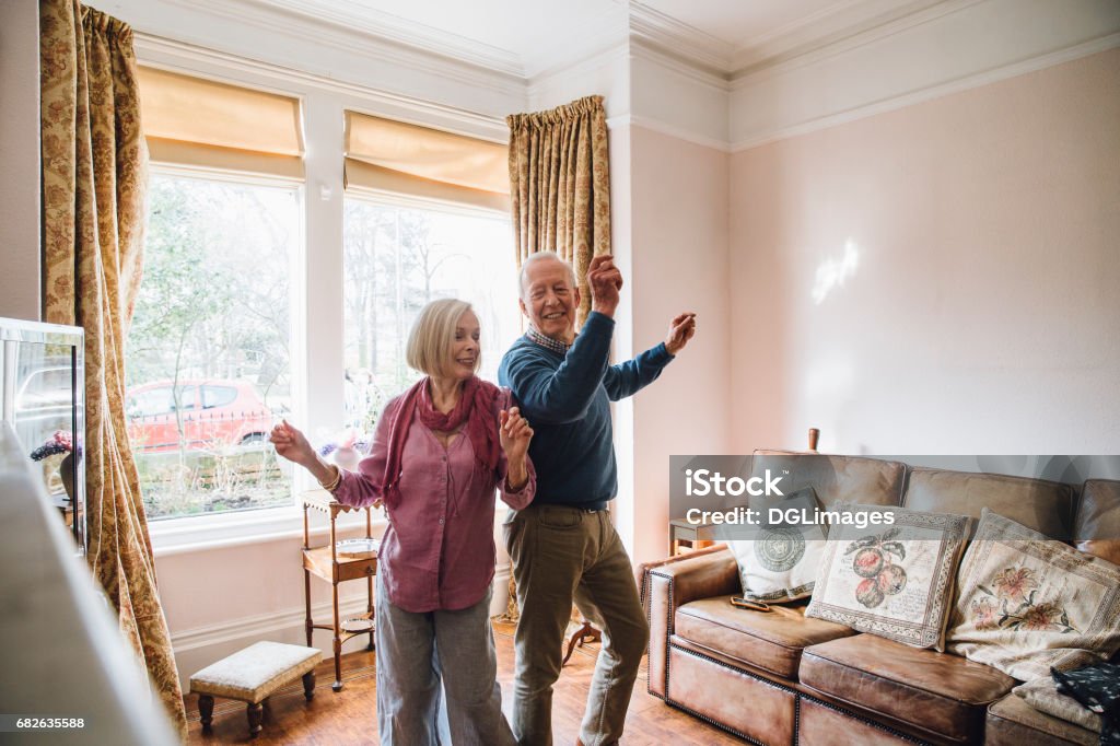 Seniors Dancing At Home Senior couple are enjoying a dance in the living room of their home. Dancing Stock Photo