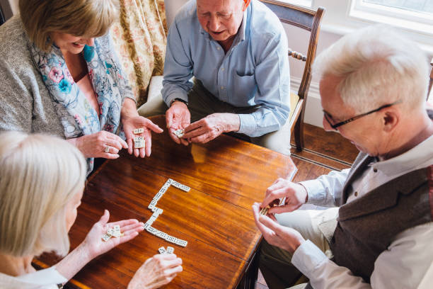 senioren spielen domino - group of people aging process home interior indoors stock-fotos und bilder