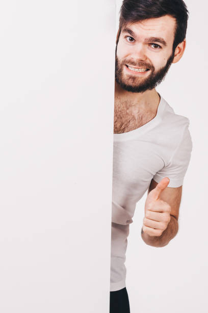 istock unshaved man in white t-shirt holding a blank white board 682639726