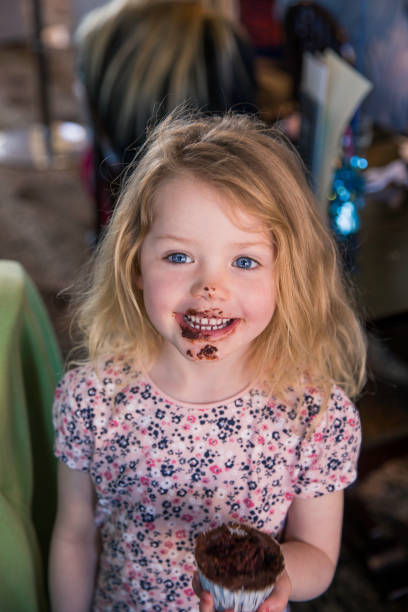 A young asian girl eating a peanut butter and jelly sandwich.