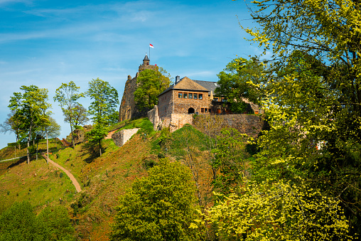 Saarburg, Germany - April 20, 2017: Historic castle on a hill of city Saarburg. It is located in the city center with many trees around.