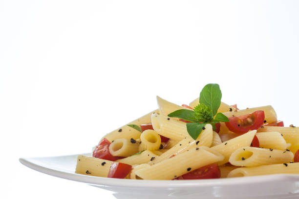 Penne rigate with cherry tomatoes and black pepper on white background
