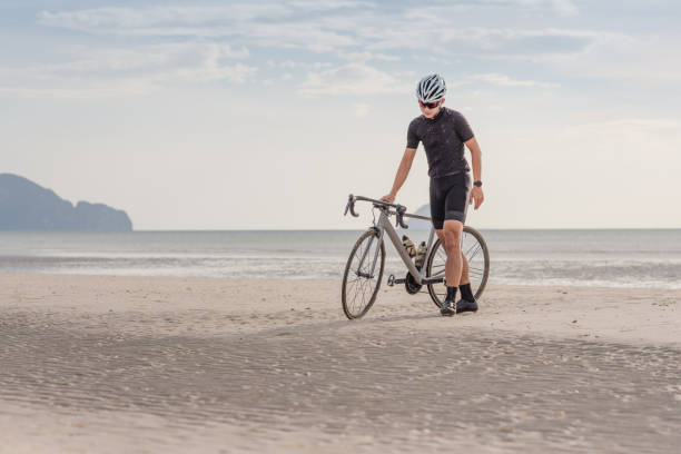 istock Young asian cyclist man ride  bicycle  the beach at the sunset 682675804