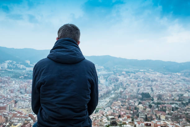 Young casual teenager enjoying Barcelona cityscape in a winter day at dusk. Rear view.