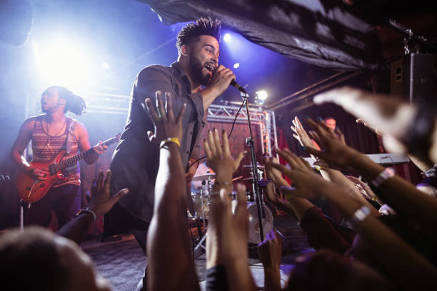 istock Male singer performing on stage by crowd at nightclub 682682734