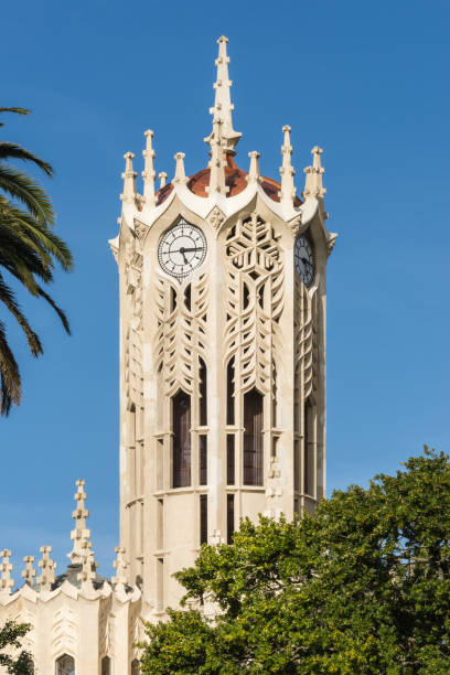 Closeup of Clock tower top of Auckland University. Auckland, New Zealand - March 5, 2017: Closeup of White clock tower top of Auckland University under blue sky. Some green tree leaves. albert park stock pictures, royalty-free photos & images