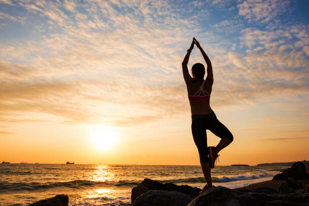 istock Young woman silhouette practicing yoga on the sea beach at sunset 682682992