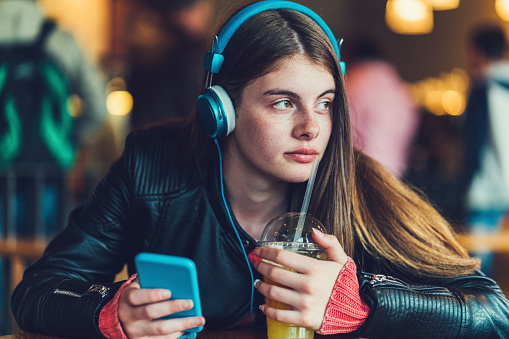 Young girl in cafe with headphones learning English