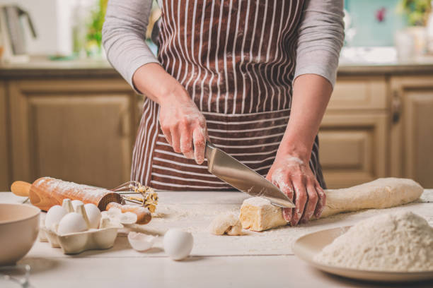 istock Close-up view of two woman's hands cut knife dough 682692578