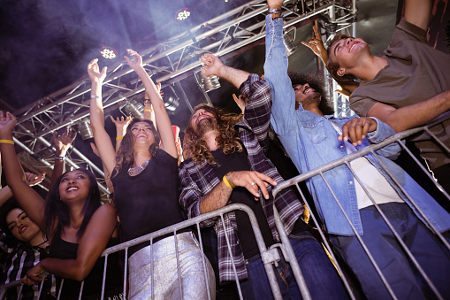Low angle view of fans enjoying at nightclub during music festival