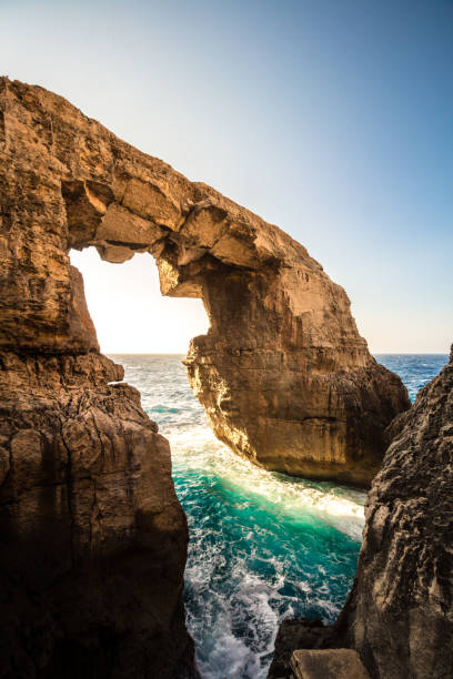 The stone sea arch at wied il-Mielah, Gozo, Malta. Sunny weather, bright sunlight golden hour. stock photo