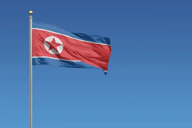 Flag of North Korea in front of a clear blue sky