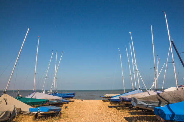 Small sailing boats lined up near the sea on the sand at Whitstable, Kent, United kingdom stock photo