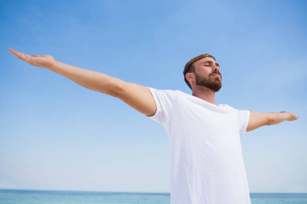 istock Man with arms outstretched exercising at beach 682776138
