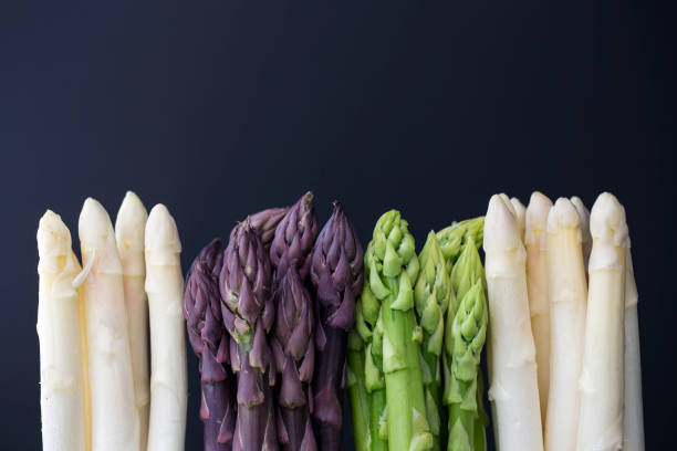 variation of asparagus white, green and purple asparagus on dark background asparagus stock pictures, royalty-free photos & images