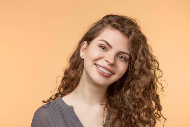 curly hair woman with brackets curly hair woman with brackets on biege background brace stock pictures, royalty-free photos & images