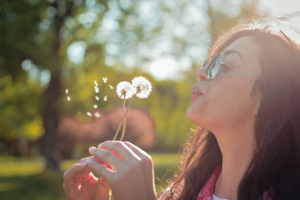istock Beautiful young woman blowing dandelion 682821788