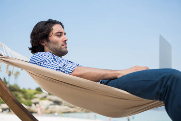 istock Side view of man using laptop while relaxing in hammock 682828912