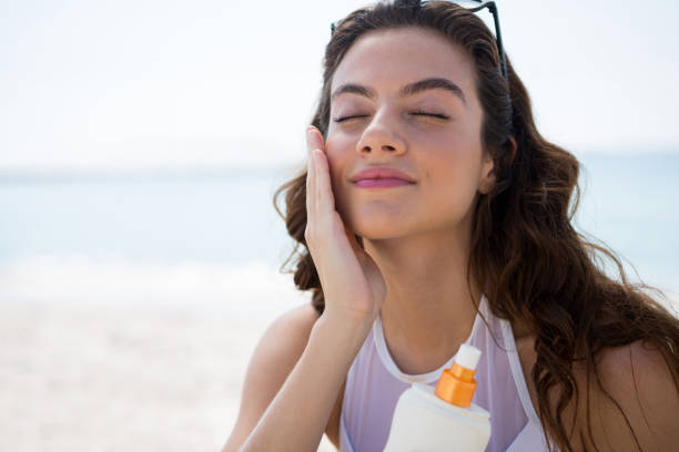 女性の顔に sunscream を適用することのクローズ アップ
