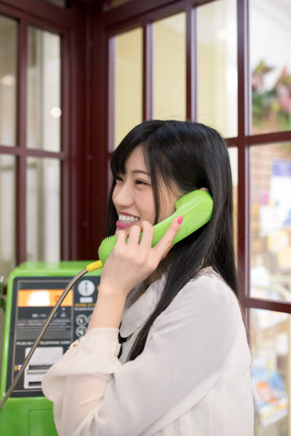 幸せな��若い女の電話ボックスで電話で話して - pay phone ストックフォトと画像