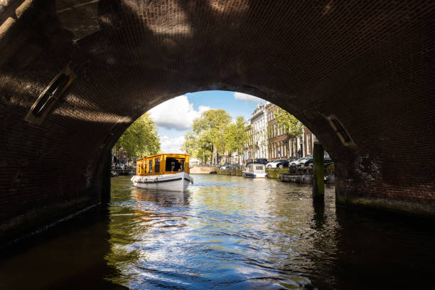 Tourboat about to go under a bridge on Amsterdam canal stock photo