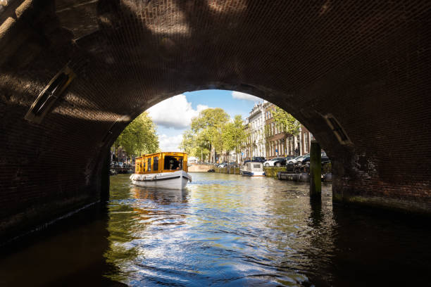 Tourboat para entrar debaixo de uma ponte no canal de Amsterdam - foto de acervo