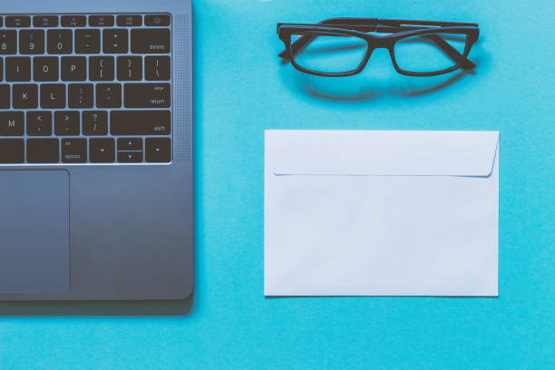 istock Eyeglasses, white paper envelope and laptop. Work space. Blue background. Top view. 682872730