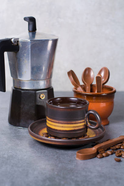 istock Black arabica coffee pouring from the coffee maker in cup and coffee beans on grey background with chocolade spoons 682876556