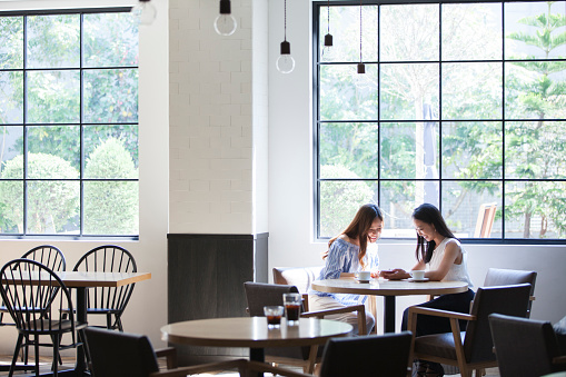 Two college girls spend at restaurants with big windows.